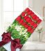 Caja de 18 rosas rojas frescas y alstroemerias blancas, con un elegante moño burdeos, sobre una mesa de mármol con fondo difu