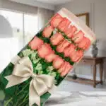 Caja de 18 rosas rosadas frescas y vibrantes con un elegante moño beige, presentadas en un fondo sofisticado y bien iluminado