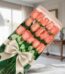 Caja de 18 rosas rosadas frescas y vibrantes con un elegante moño beige, presentadas en un fondo sofisticado y bien iluminado