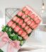 Caja de 24 rosas rosadas frescas con moño de seda rosa, dispuestas elegantemente en un fondo luminoso y moderno, ideal para e