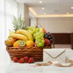 Canasta de mimbre llena de frutas frescas como piña, plátanos, uvas verdes y rojas, peras, manzanas, naranjas, kiwi y fresas,