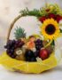 Canasta de Frutas Draco con uvas, manzanas, duraznos, kiwis, piña y arreglo floral de rosas, girasol y flores blancas sobre m