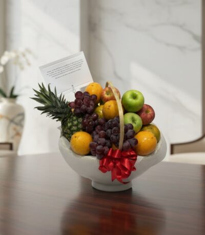 Canasta de frutas gourmet con piña, uvas, manzanas y naranjas, sobre una mesa de madera pulida en un entorno elegante.