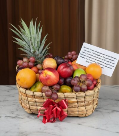 Canasta de frutas Musca con piña, uvas, manzanas, naranjas y duraznos, presentada en un entorno elegante con fondo de madera
