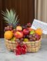 Canasta de frutas Musca con piña, uvas, manzanas, naranjas y duraznos, presentada en un entorno elegante con fondo de madera
