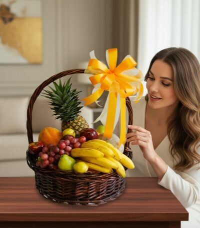 Mujer joven y elegante admirando una canasta de frutas Sirio con piña, uvas, plátanos y otras frutas frescas, decorada con un