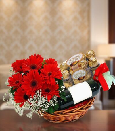 Cesta de regalo ROMA con gerberas rojas, vino tinto y chocolates Ferrero Rocher, ideal para ocasiones especiales.
