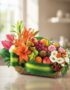Cesta de frutas THALIA con lirios naranjas, anturios rosas, rosas, uvas, manzanas, kiwis y naranjas, sobre mesa de madera cla