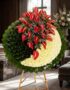 Impresionante corona fúnebre con anthuriums rojos y crisantemos blancos, presentada en una sala de velación premium con luz n