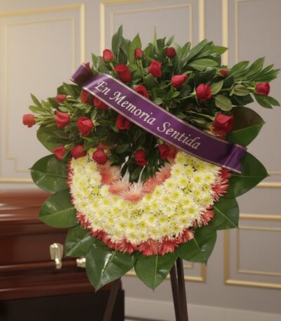Corona fúnebre Adiós Sincero con rosas rojas y crisantemos blancos, cinta morada 'En Memoria Sentida', en sala de velación pr