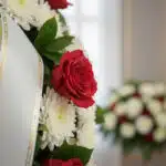 Fotografía macro premium de la Corona Fúnebre Adiós Sincero, mostrando rosas rojas y crisantemos blancos con rocío sutil y ci