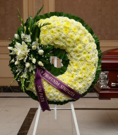 Corona fúnebre Bethesda con flores blancas y amarillas, cinta morada con mensaje 'En Profunda Simpatía', junto a un ataúd en