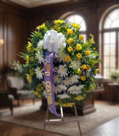 Corona fúnebre 'Estamos Contigo' con flores amarillas y blancas, lazo morado, en sala de velación premium con luz natural sua