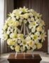 Corona fúnebre Homenaje Gadriel con lirios, rosas y crisantemos blancos, sobre un caballete en una sala de velación premium c
