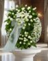 Corona fúnebre Legado Jacob con rosas blancas, lirios y margaritas, lazo de tul, en sala de velación premium con luz natural