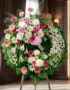 Corona fúnebre solemne "Homenaje a Mathias" con lirios blancos, gerberas rosas y crisantemos blancos, en una sala de velación