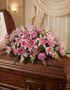 Cubre caja fúnebre Ifigenia con rosas y lirios rosados, eucalipto y follaje verde, elegantemente dispuesto sobre un ataúd de