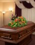 Cubre caja fúnebre 'Paz Eterna' con flores frescas y vibrantes sobre un ataúd de madera oscura en un entorno elegante y bien