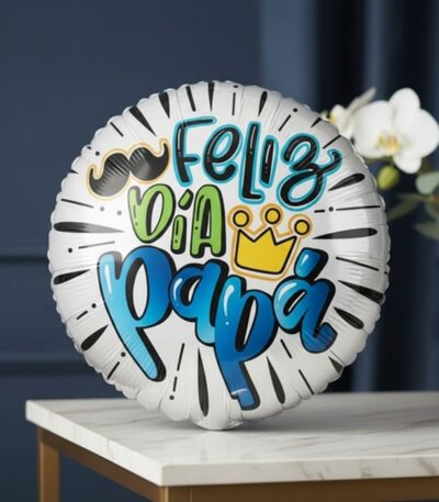 Globo metalizado blanco con la frase 'Feliz Día Papá' en colores vibrantes, bigote y corona, sobre una mesa de mármol con orq