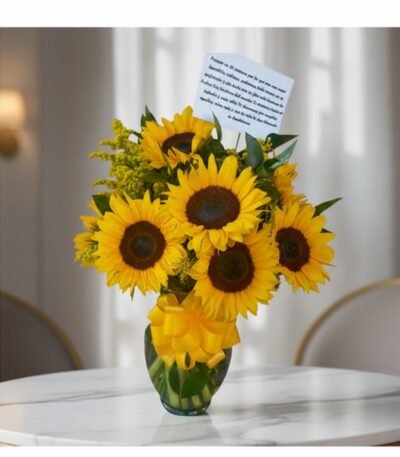 Jarrón de cristal con doce girasoles vibrantes y follaje verde, atado con un lazo amarillo, sobre una mesa de mármol en un en