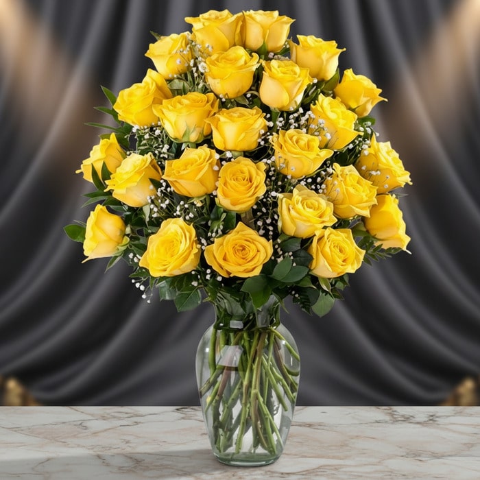Jarrón de cristal con 24 rosas amarillas frescas y vibrantes, dispuestas elegantemente sobre una mesa de mármol con un fondo