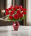 Jarrón Amor Incondicional con un hermoso arreglo de rosas rojas frescas y follaje verde, sobre una mesa de mármol en un elega