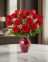 Jarrón Amor Incondicional con un hermoso arreglo de rosas rojas frescas y follaje verde, sobre una mesa de mármol en un elega
