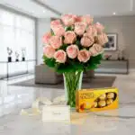 Jarrón Decídete con un hermoso arreglo de rosas rosadas frescas, acompañado de una caja de chocolates Ferrero Rocher, sobre u