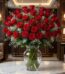 Impresionante jarrón GINEVRA con 80 rosas rojas frescas y abiertas, rodeadas de follaje verde y pequeñas flores blancas, sobr