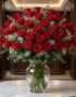Impresionante jarrón GINEVRA con 80 rosas rojas frescas y abiertas, rodeadas de follaje verde y pequeñas flores blancas, sobr