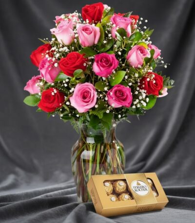 Jarrón Te Extraño con un hermoso arreglo de rosas rojas y rosadas, complementado con follaje verde y pequeñas flores blancas,