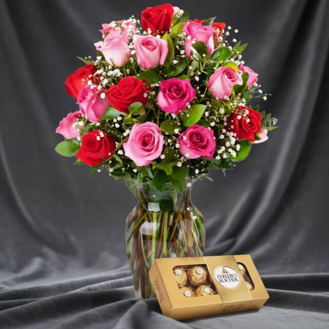 Jarrón Te Extraño con un hermoso arreglo de rosas rojas y rosadas, complementado con follaje verde y pequeñas flores blancas,