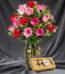 Jarrón Te Extraño con un hermoso arreglo de rosas rojas y rosadas, complementado con follaje verde y pequeñas flores blancas,