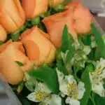 Primer plano extremo de un arreglo floral con rosas salmón y alstroemerias blancas, mostrando texturas hiperrealistas y gotas