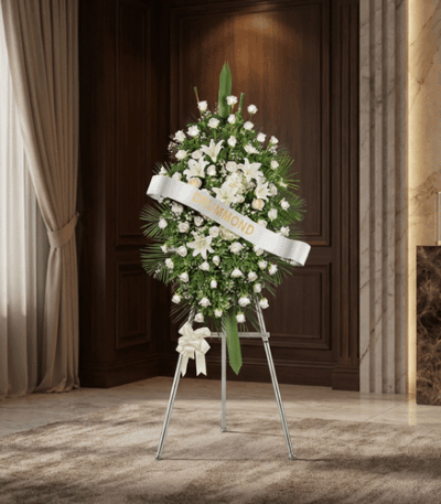 Pedestal conmemorativo Legado de Marcos con arreglo floral fúnebre blanco, lirios y rosas, en sala de velación elegante con i