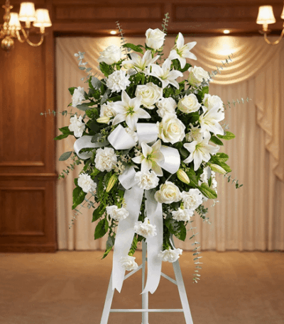 Pedestal conmemorativo Santuario para el Homenaje a PAREDES, con un elegante arreglo floral funerario de rosas blancas, lirio