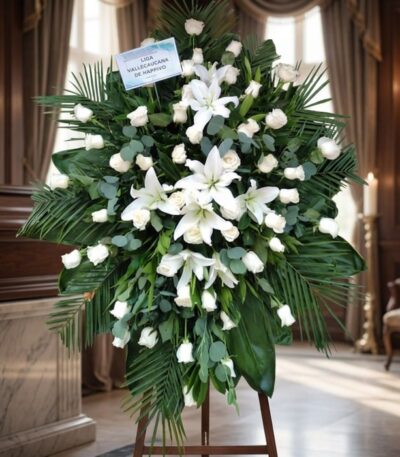 Pedestal fúnebre 'Eternidad' con rosas blancas, lirios y follaje verde, en una elegante sala de velación con luz natural suav