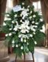 Pedestal fúnebre 'Eternidad' con rosas blancas, lirios y follaje verde, en una elegante sala de velación con luz natural suav