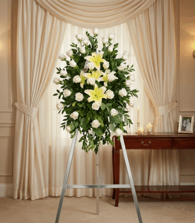 Pedestal fúnebre "Luz de Jacinta" con rosas blancas y lirios amarillos, en una elegante sala de velación con iluminación cáli