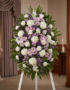 Impresionante pedestal fúnebre de homenaje con flores blancas, lilas y rosadas, ideal para honrar la memoria de Patricio en u