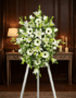 Pedestal fúnebre Inmaculada con lirios blancos, gerberas y follaje verde, presentado en una elegante sala de velación con ilu