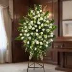 Pedestal fúnebre 'Nunca te Olvidaré' con rosas blancas, lirios y follaje verde, presentado en una sala de velación premium co