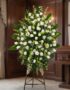 Pedestal fúnebre 'Nunca te Olvidaré' con rosas blancas, lirios y follaje verde, presentado en una sala de velación premium co