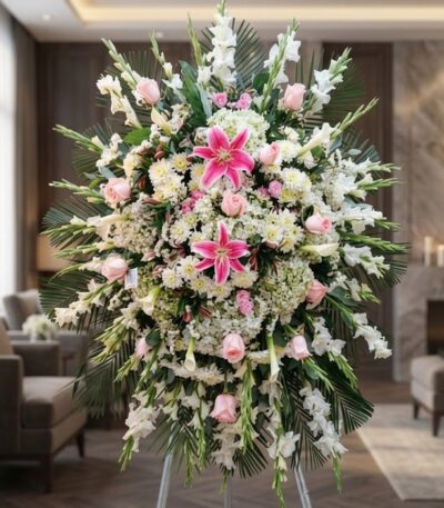 Pedestal fúnebre 'Pasión' con lirios rosados, rosas pálidas y gladiolos blancos, en sala de velación premium con luz natural.