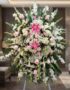Pedestal fúnebre 'Pasión' con lirios rosados, rosas pálidas y gladiolos blancos, en sala de velación premium con luz natural.