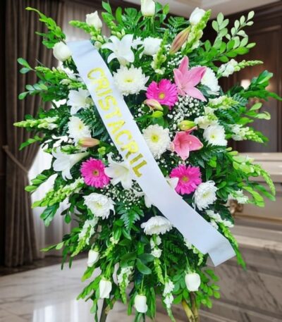 Pedestal fúnebre Sagrado con flores blancas, lirios, crisantemos y toques de gerberas rosas, en una sala de velación premium