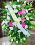 Pedestal fúnebre Sagrado con flores blancas, lirios, crisantemos y toques de gerberas rosas, en una sala de velación premium