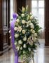 Pedestal fúnebre Salvación con rosas blancas, lirios y follaje verde, presentado en una sala de velación premium con luz natu