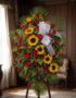 Pedestal fúnebre solemne con rosas rojas, girasoles y follaje verde, presentado en una elegante sala de velación con luz natu