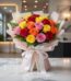 Ramillete o bouquet de 18 rosas multicolor (rojas, amarillas, naranjas, rosas) con empaque coreano elegante sobre mesa de már